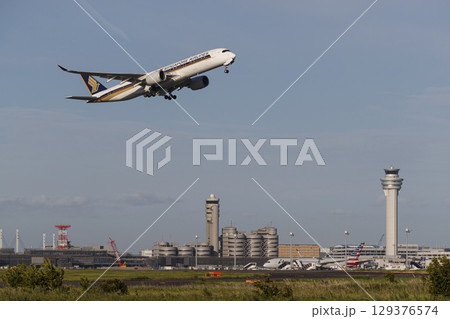 管制塔をバックに離陸する飛行機 129376574