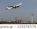 管制塔をバックに離陸する飛行機 129376576