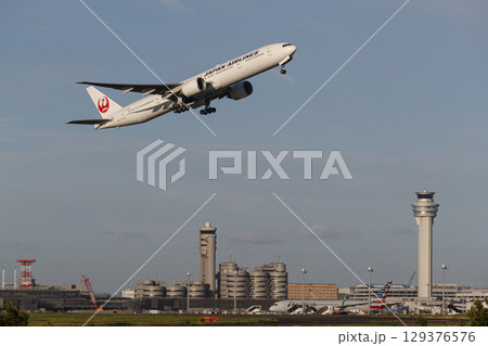 管制塔をバックに離陸する飛行機 129376576