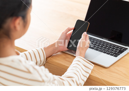家でスマホを操作する中学生の女の子 129376773