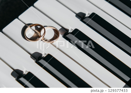 two wedding rings resting on piano keys create beautiful symbol love and music in harmonious setting two wedding rings resting on piano keys create beautiful symbol love and music in harmonious setting 129377433