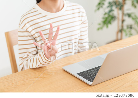 パソコンの前で4本指を立てる中学生の女の子 129378096