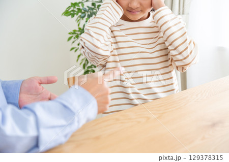 お父さんに叱られて耳を塞ぐ中学生の女の子 129378315
