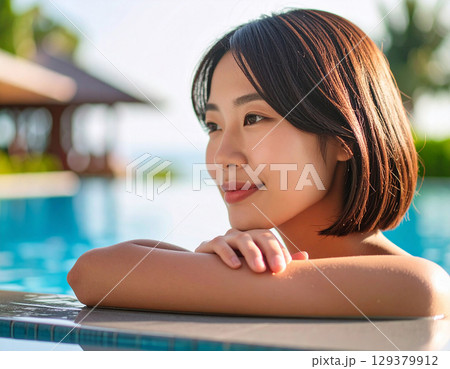プールサイドで微笑む若い女性/ Young woman smiling by the pool プールサイドで微笑む若い女性/ Young woman smiling by the pool 129379912