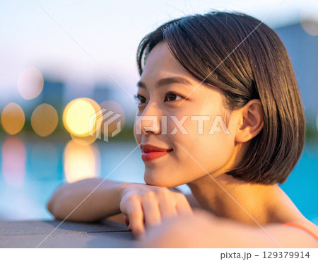 プールサイドで微笑む若い女性/ Young woman smiling by the pool 129379914