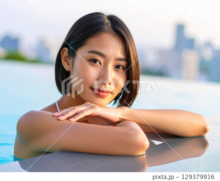プールサイドで微笑む若い女性/ Young woman smiling by the pool プールサイドで微笑む若い女性/ Young woman smiling by the pool 129379916