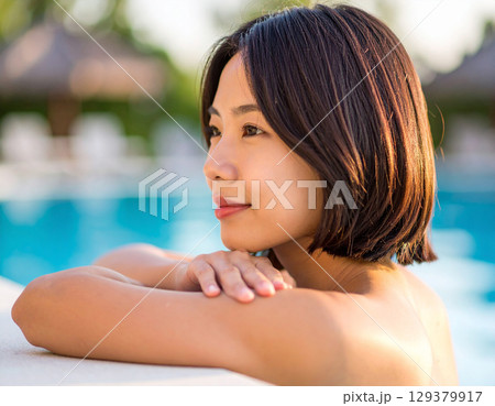 プールサイドで微笑む若い女性/ Young woman smiling by the pool プールサイドで微笑む若い女性/ Young woman smiling by the pool 129379917