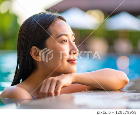 プールサイドで微笑む若い女性/ Young woman smiling by the pool 129379959