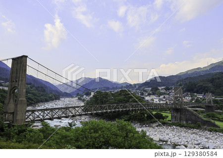 長野県南木曽町に架かる歴史的な吊り橋桃介橋と山並みの風景 129380584