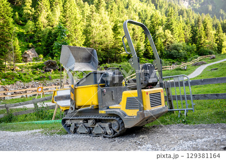 Compact tracked dumper at construction site in alpine mountain landscape 129381164