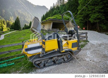 Compact tracked dumper at construction site in alpine mountain landscape 129381165