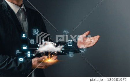 A hand holds a cloud computing icon, symbol data storage, secure backup, and management for uploading, downloading, and transfer files in a connected digital network and internet service environment. 129381973