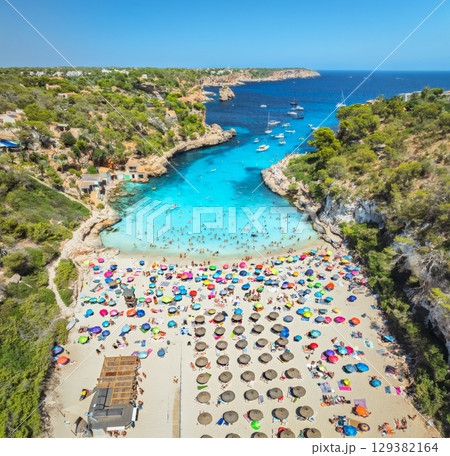 Aerial view of colorful umbrellas on sandy beach, swimming people Aerial view of colorful umbrellas on sandy beach, swimming people 129382164