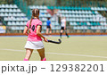 Field hockey player in pink uniform prepares for action during a match 129382201