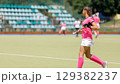 Young athlete plays field hockey in bright pink uniform. Copy space image 129382237