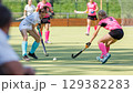 Competitive field hockey match featuring players in action on sunny day 129382283