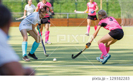 Competitive field hockey match featuring players in action on sunny day 129382283