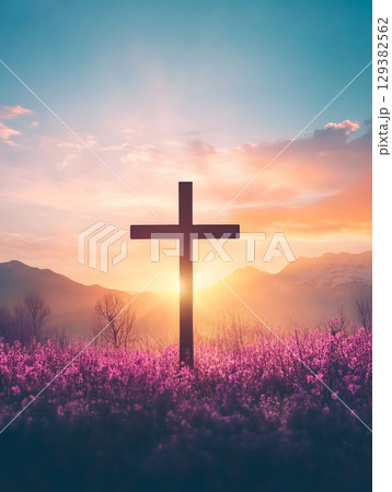 Crucifix silhouette against a vibrant sunset on a mountain backdrop with blooming flowers 129382562