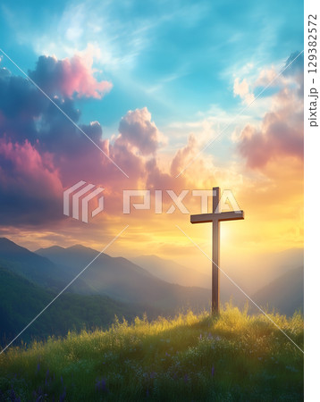 A serene crucifix symbol stands on a mountain during a vibrant sunset over the landscape 129382572