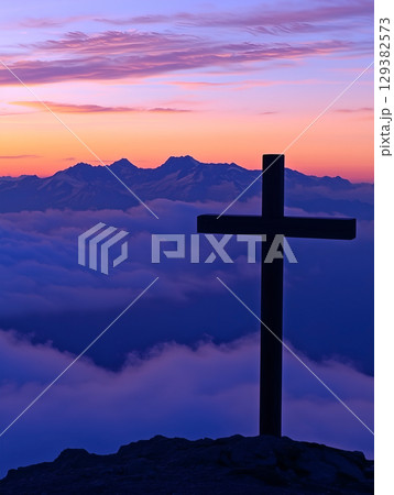 A silhouette of the crucifix against a vibrant mountain sunset casting a serene aura A silhouette of the crucifix against a vibrant mountain sunset casting a serene aura 129382573