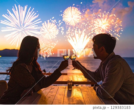 海辺で花火を眺めながら乾杯するカップルのロマンチックな夏の夜景 129383183