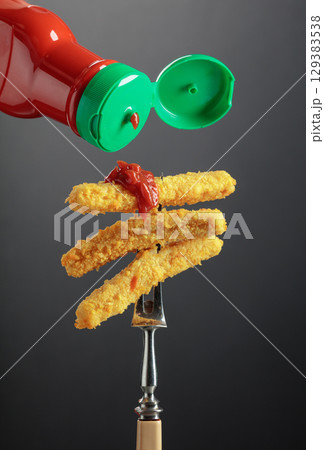 Fish fingers with ketchup on a fork. 129383538
