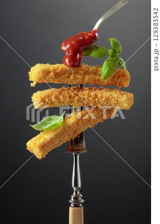 Fish fingers with basil and ketchup on a fork. 129383542