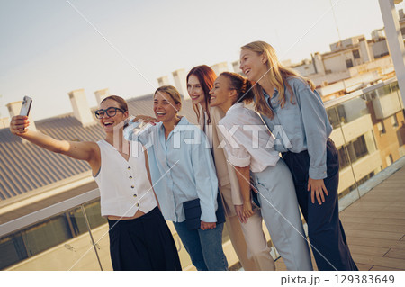 A group of close friends happily enjoying a beautiful sunny day together on a rooftop 129383649