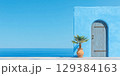 Beautiful blue wall with wooden door and potted palm against a clear sky and ocean view 129384163