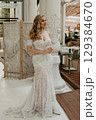 Beautiful slim blonde poses in boho wedding dresses and an embroidered corset on a summer terrace 129384670