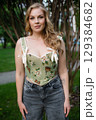 Beautiful slim blonde poses in boho wedding dresses and an embroidered corset on a summer terrace 129384682