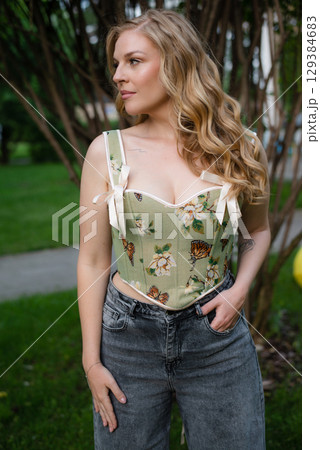 Beautiful slim blonde poses in boho wedding dresses and an embroidered corset on a summer terrace Beautiful slim blonde poses in boho wedding dresses and an embroidered corset on a summer terrace 129384683