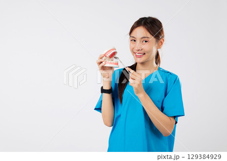 Asian woman, smile, oral model holding dental mirror, showing teeth, in clinic, nurse with dental tool displays the perfect dental care example, headshot isolated studio white background Asian woman, smile, oral model holding dental mirror, showing teeth, in clinic, nurse with dental tool displays the perfect dental care example, headshot isolated studio white background 129384929