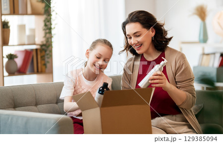 Mother and daughter are unpacking cardboard 129385094