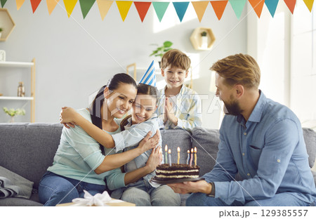 Big happy family celebrates daughter's birthday with cake adorned candles. Daughter's birthday favorite desserts and decorations fill room as they commemorate her special day daughter's birthday. 129385557