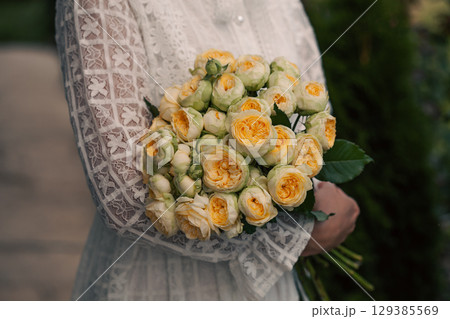 Bouquet in female hands. Bunch of Living yellow roses. 129385569