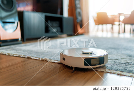 White robotic vacuum cleaner on wooden floor 129385753