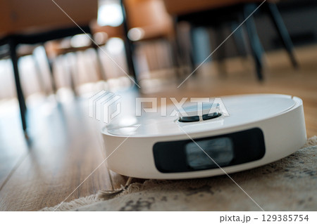 White robotic vacuum cleaner on wooden floor 129385754