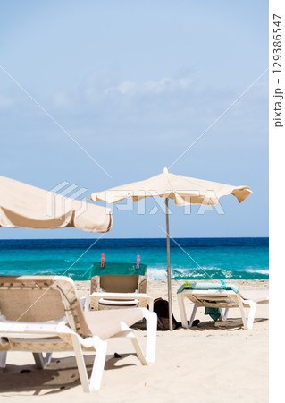 海岸沿いの広々とした砂浜に並べられたパラソルとビーチベッド　フエルテベンテュラ島にて 129386547