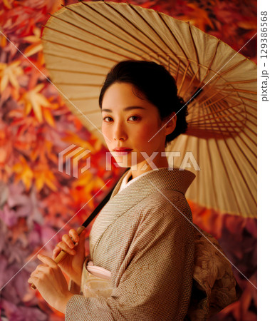秋の紅葉柄の前で立つ着物を着た女性 129386568