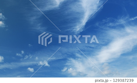 Enjoy the breathtaking view of blue skies with fluffy clouds and contrails across the sky 129387239