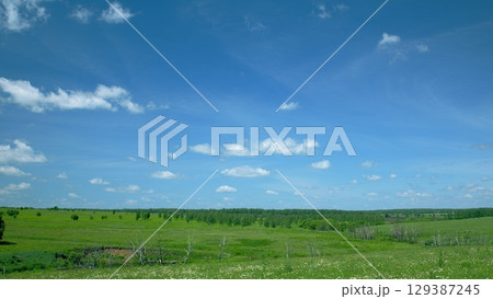 A Beautifully Serene and Picturesque Green Landscape Stretching Under a Radiant Bright Blue Sky 129387245