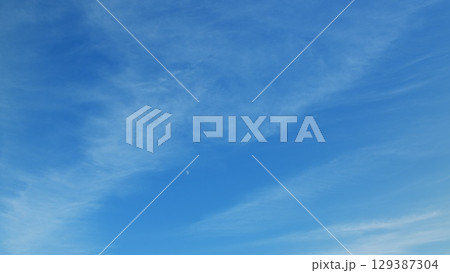 A Beautiful Clear Blue Sky Adorned with Soft Clouds and a Glowing Moon Shining Brightly Above 129387304