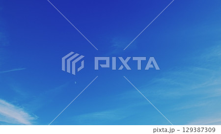 A stunning and vibrant blue sky adorned with wispy, delicate clouds floating gracefully above A stunning and vibrant blue sky adorned with wispy, delicate clouds floating gracefully above 129387309