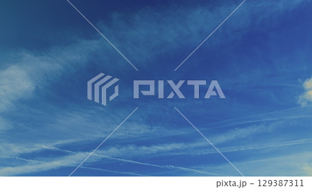 A Beautiful Sky Appearing with Contrails and Fluffy, Soft Clouds Floating Gracefully 129387311