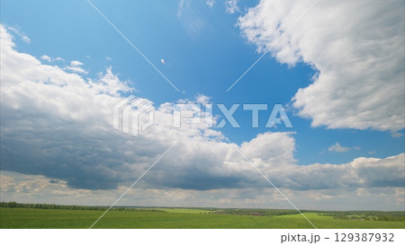A serene, tranquil, cloudy sky spreads beautifully over lush green fields beneath it A serene, tranquil, cloudy sky spreads beautifully over lush green fields beneath it 129387932