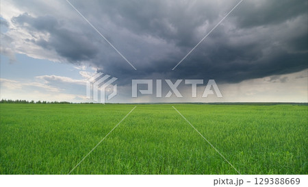 Dramatic and Unpredictable Weather Occurring Above a Lush and Vibrant Green Landscape 129388669
