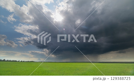 Dramatic Skies Filled with Clouds Hovering Over a Lush and Expansive Green Field Dramatic Skies Filled with Clouds Hovering Over a Lush and Expansive Green Field 129388725