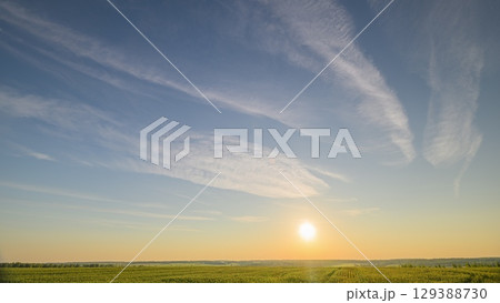 Experience a serene sunrise over verdant fields, a breathtaking landscape of beauty and calm 129388730