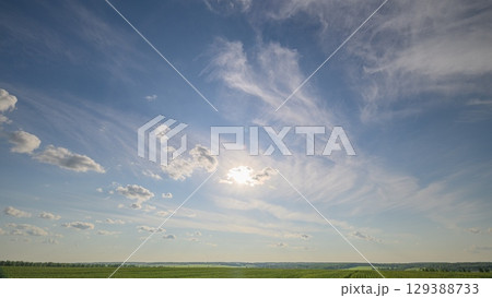 A Beautiful Sunny Sky with Wispy Clouds Gracefully Floating Over Lush Green Fields A Beautiful Sunny Sky with Wispy Clouds Gracefully Floating Over Lush Green Fields 129388733